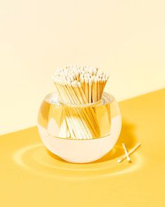 a cup filled with gold and white toothbrushes on top of a yellow table