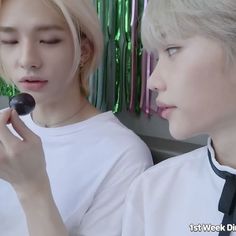 two young men sitting next to each other holding donuts in front of their faces