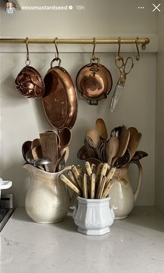 pots and pans are hanging on the wall with utensils attached to them