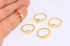 four pieces of gold ring sitting on top of a white table next to someone's hand