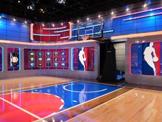 an empty basketball court with several large screens on the wall