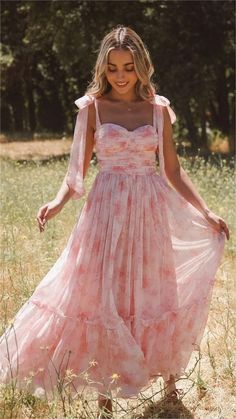 a woman in a pink dress is walking through the grass