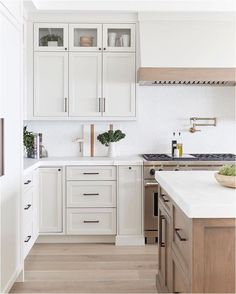 a kitchen with white cabinets and wood floors