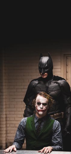 the dark knight and joker are sitting at a table