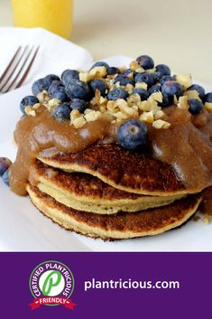 a stack of pancakes with blueberries and walnuts on top, topped with chocolate syrup