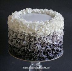 a black and white cake with ruffles on top sitting on a silver plate