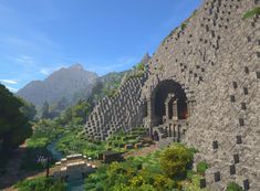 an image of a stone structure in the middle of some trees and bushes with mountains in the background