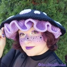 a woman wearing a purple hat with white polka dots on her face and black hair