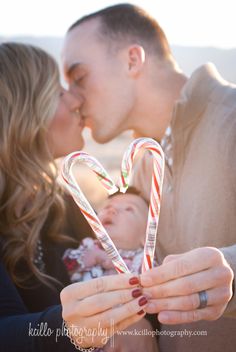 a man and woman kissing while holding two candy canes