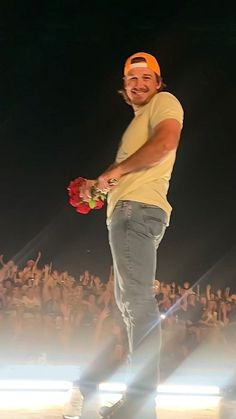 a man standing on top of a stage holding a bouquet of flowers in his hand