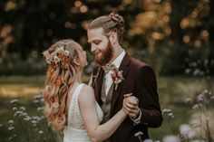 a bride and groom are standing in the middle of some wildflowers with their arms around each other