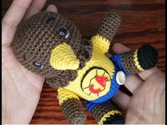 a hand is holding a small crocheted teddy bear