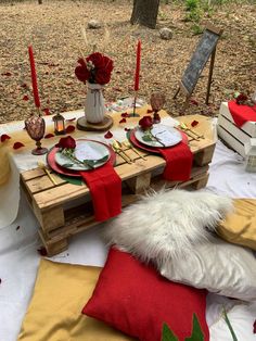 the table is set with red and white plates, napkins, candles and flowers