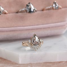 an engagement ring sits on top of a white marble slab next to pink velvet purse