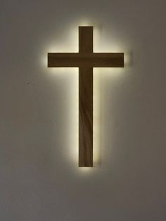 a wooden cross is lit up on the wall with light coming from it's sides