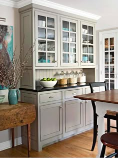 a large kitchen with white cabinets and wooden table in front of the counter top area