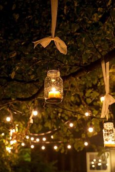 mason jar lights hanging from a tree at night