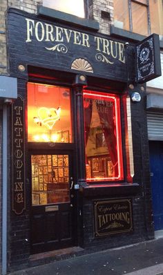 the storefront of a tattoo parlor with neon lights in it's window display