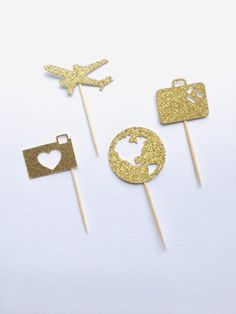 gold glitter cake toppers with heart, airplane and earth on them are ready to be cut out