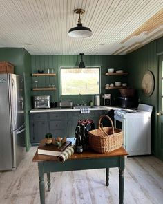 a kitchen with green painted walls and wooden flooring, along with a small table in the center