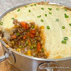 a large pot filled with mashed potatoes and meat covered in gravy on top of a wooden table