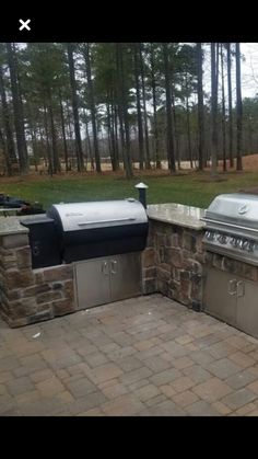 an outdoor kitchen with grills and seating