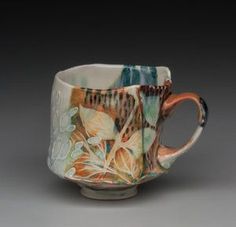 a coffee cup is decorated with flowers and leaves on it's sides, while the bottom part of the mug has an orange rim