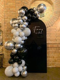 an arch made out of black and white balloons