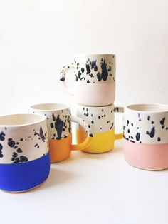 five different colored coffee mugs sitting next to each other on a white table top