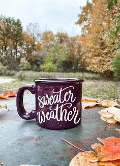 a purple coffee mug sitting on top of a table covered in leaves and fallen leaves