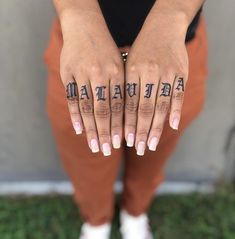 a woman's hands with tattoos on their fingers and the word man written in cursive writing