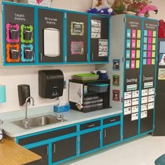 a kitchen area with blue cabinets and lots of magnets on the wall