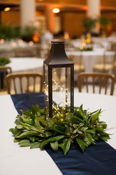 a lantern on top of a table with greenery