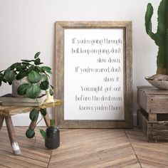 a wooden table with a potted plant and a framed quote