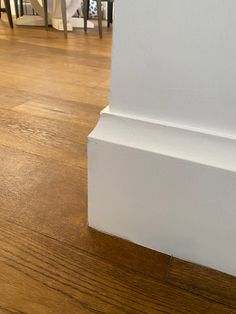 the corner of a room with wood floors and white walls