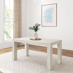 a white table sitting on top of a wooden floor next to a potted plant