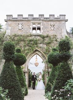 the bride and groom are standing in front of an archway with topiary bushes on either side