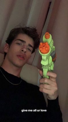 a young man is holding up a toy in front of his face with the words give me all our love written on it