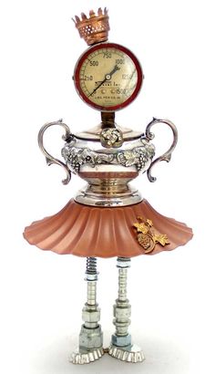 a clock that is sitting on top of a lamp shade with two legs and a crown