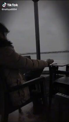 a person sitting in a chair looking out at the water from a deck area on a boat