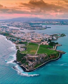 an aerial view of the city and its surrounding coastline at sunset, with water in foreground