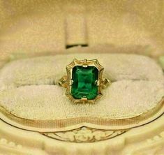 an antique ring with a green stone set in it's center, sitting on a white cloth