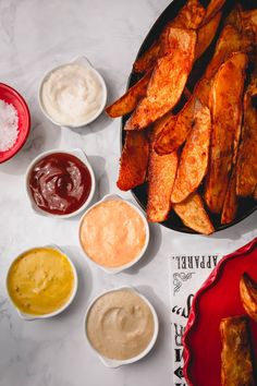 several different sauces and condiments on a white counter top next to some fried food