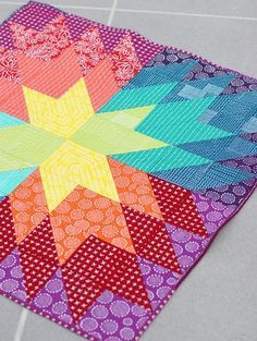 a multicolored patchwork quilt on the ground with one star in the center