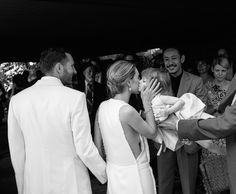 a group of people standing next to each other in front of a man holding a baby