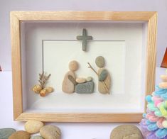 a wooden frame with some rocks in it and a cross on the wall behind it