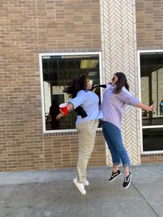 two women jumping in front of a brick building