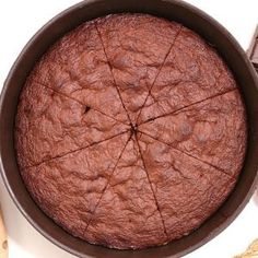 a chocolate cake in a brown pan on a white surface with other baking utensils