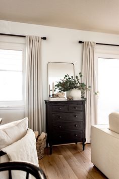 a living room with a dresser, mirror and couch