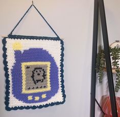 a crocheted wall hanging next to a plant